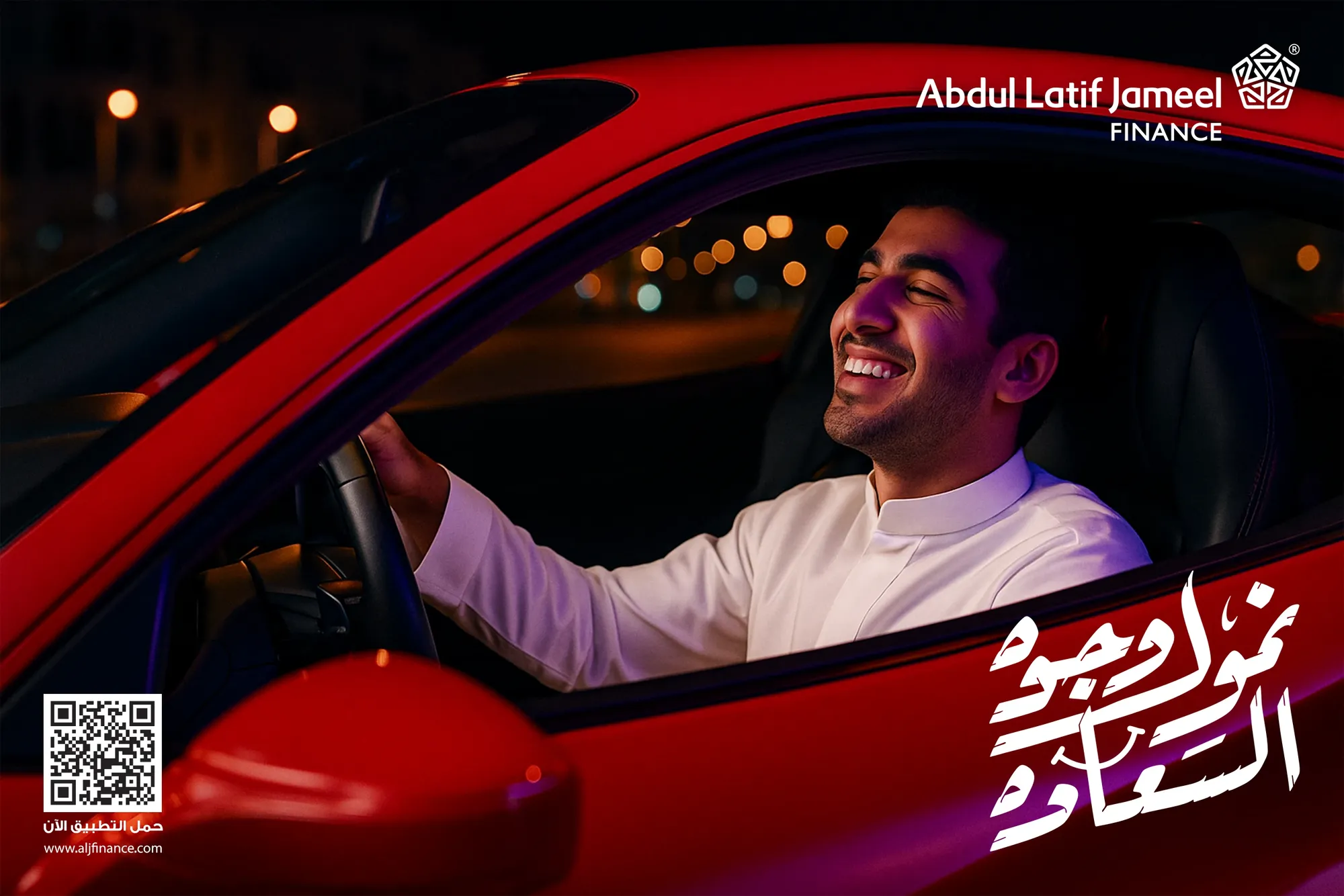 A young man laughing at the wheel of a red car at night