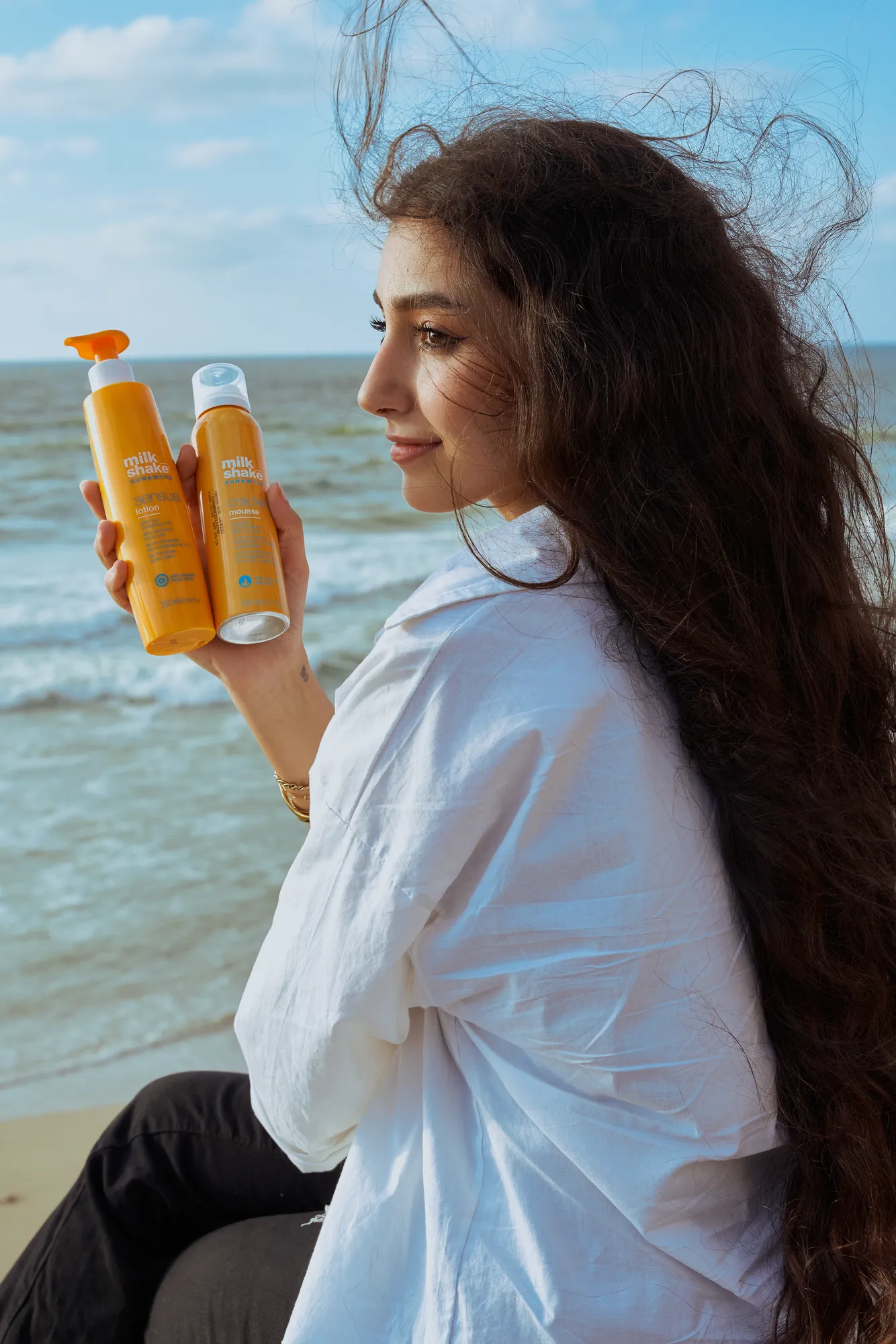 A woman on the beach holding two Capello bottles