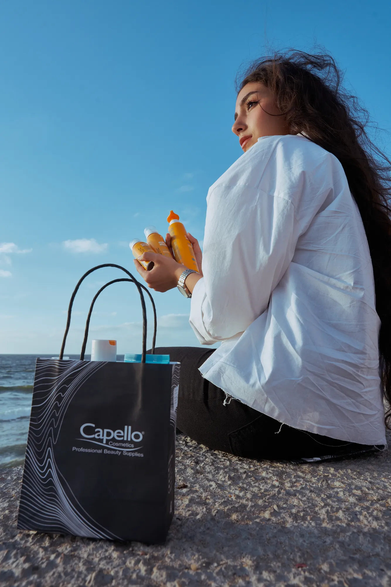 A woman sitting on rocks with a Capello bag
