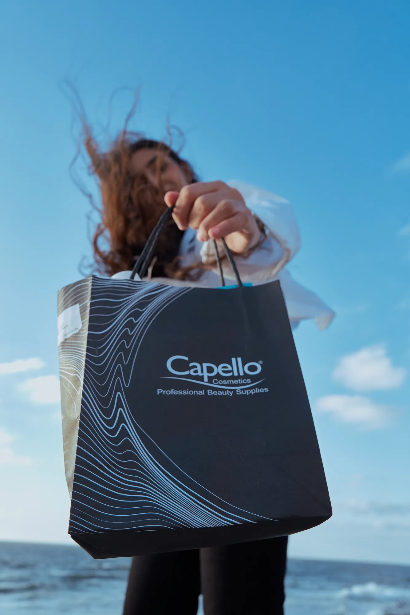 A Capello shopping bag held up against the sky