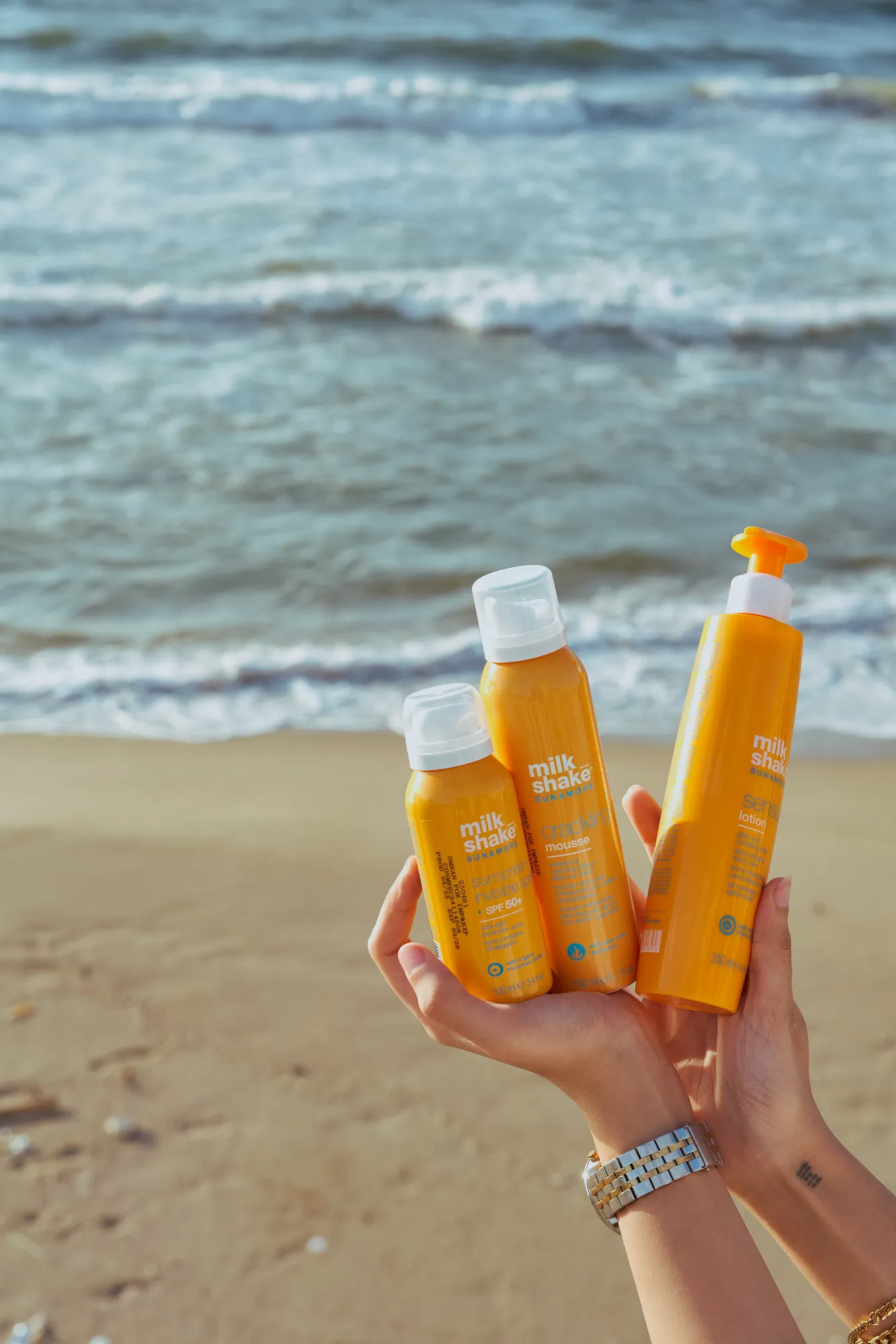 Hands holding three Capello bottles over the sand