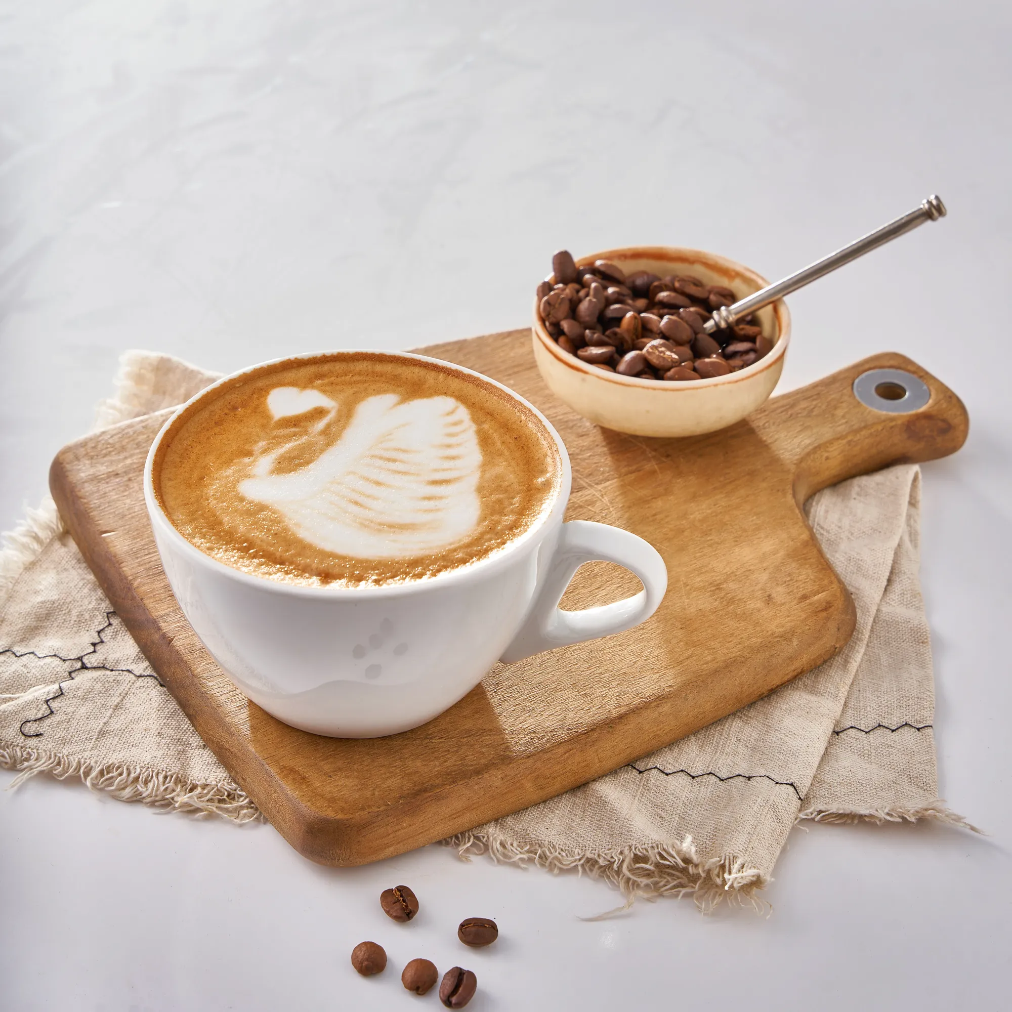 A latte with swan latte art and coffee beans